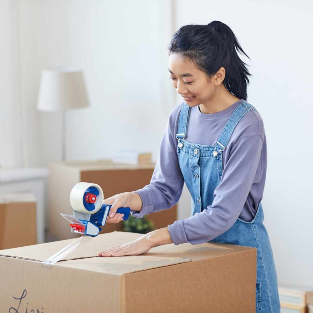 Smiling young woman packing her last box before she moves internationally with Santa Fe Relocation.